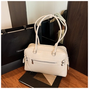 Detail view of beige leather bowling bag with zipper pocket and metal buckle accents