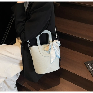 Dettaglio della borsa a secchiello celeste con motivo litchi e foulard in seta