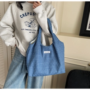 Detail of blue denim tote bag with white polka dots and minimalist fabric label