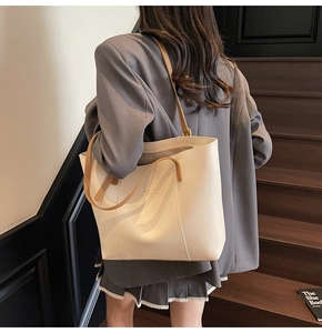 Détail d'un sac cabas crème avec anses marron porté à l'épaule dans un décor doux
