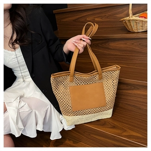 Detail of dual-tone straw tote bag with woven mesh texture and brown leather patch