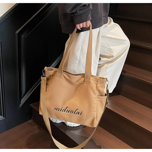 Detail of khaki canvas tote bag with black logo and side pocket on wooden background