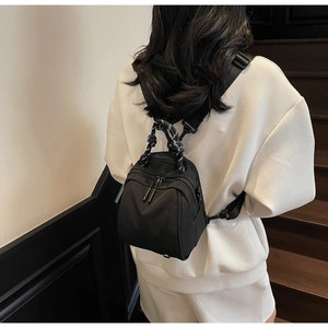Close-up of lightweight black nylon backpack showing dual zippers and braided handle detail