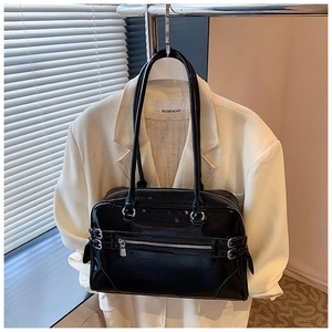 Detail of a black oily leather boston handbag styled with a beige suit on a hanger