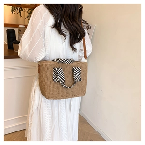 Détail du sac cabas en paille avec poignée ruban rayé et bandoulière en cuir souple