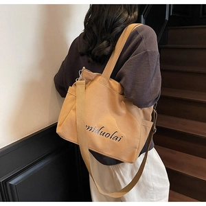 Detail of khaki canvas tote bag featuring side pockets and a long adjustable strap