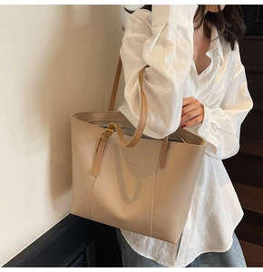 Vue latérale d'un grand sac cabas beige en cuir avec des anses marron et lettrage doré