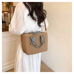 Détail d'un sac en paille tissé avec foulard rayé noir et blanc et bandoulière cuir