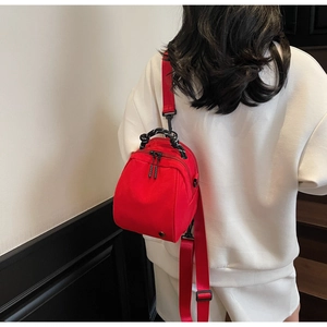Rear view of model wearing a red mini waterproof backpack with dual woven handles