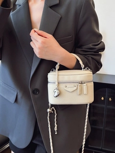 Minimalistische beige Box-Umhängetasche aus Leder mit silberner Kette am Modell