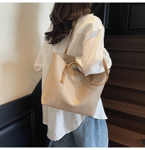 Détail d'un grand sac cabas en cuir mat beige avec de longues lanières et boucles dorées