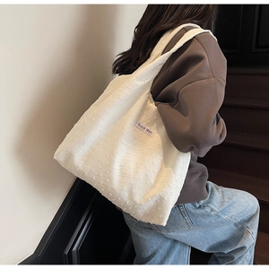 Detail of white tote bag with 3D polka dot texture and side brand woven label
