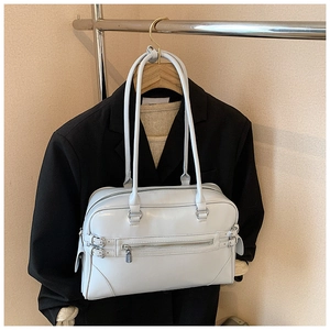 Detail of light gray crossbody boston bag with silver buckles hanging on a wooden hanger
