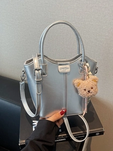 Silver metallic bucket bag with adjustable strap and cute teddy bear charm for women