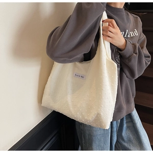 Detailed shot of large cream canvas tote bag with textured fabric and logo tag