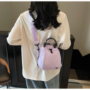 Lifestyle view of a purple mini nylon backpack with stylish woven handle on a model