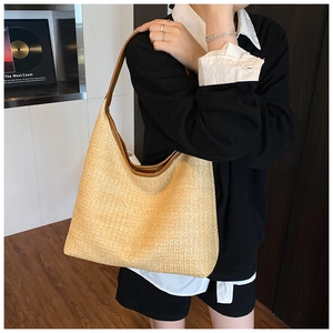 Detail showing the woven texture and leather handle of this large summer straw hobo bag