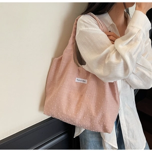 Detailed view of pale pink tote bag with textured jacquard fabric and brand label