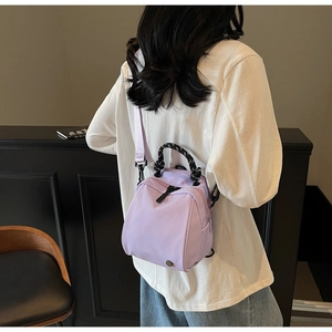 Rear view of model wearing a purple nylon mini shell backpack with woven top handle