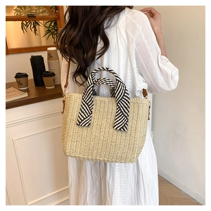 Détail du sac cabas en paille avec anses rayées noir et blanc et fine bandoulière marron