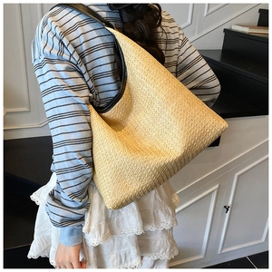 Detailed view of woven straw tote bag texture and high-quality black leather shoulder strap