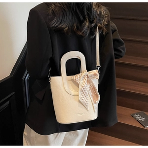 Dettaglio della borsa a secchiello bianco avorio con foulard in seta su scala vintage