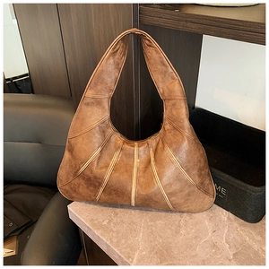Detail of a brown leather crescent hobo bag with vintage quilted texture on a stone surface