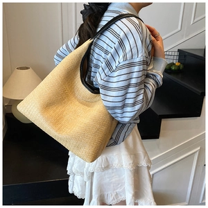 Detail of large straw woven tote bag with NO STUDY BAG text and black leather handles