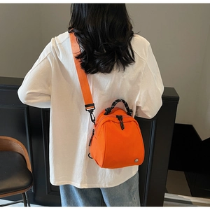 Rear view of model wearing bright orange mini nylon backpack with wide strap and rope handle