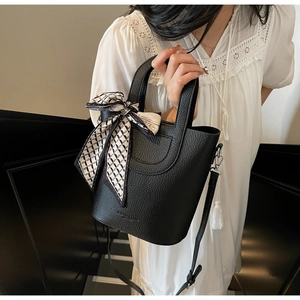 Dettaglio della borsa a secchiello in pelle nera con foulard geometrico sul manico