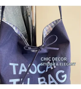 Détail du sac cabas en toile bleu avec fermeture à nœud et doublure à carreaux