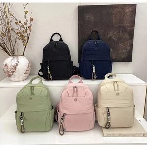 Group photo of minimalist nylon backpacks in black, blue, green, pink, and beige colors