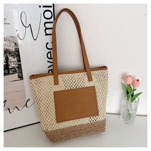 Detail of hollow woven straw tote bag with brown leather patch and dual handles
