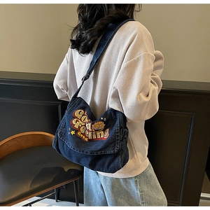 Detail of vintage denim crossbody bag featuring 'Good Feeling' embroidery on a flap cover