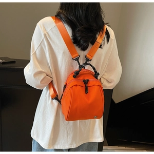 Detail view of mini orange waterproof nylon backpack with woven handle and zipper close