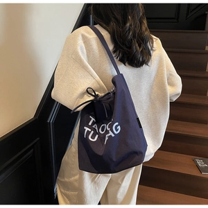 Détail du sac cabas en toile marine avec lettrage blanc et fermeture à cordon
