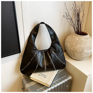 Detail view of large black Hobo bag with radial stitching on vintage metal suitcase