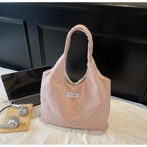 Pink fabric tote bag with textured dots shown with a laptop and headphones