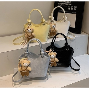 Detail of four colorful faux crocodile skin bucket bags with cute bear charm accessories