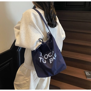 Détail du cabas en toile marine avec imprimé TOCA TU BAG et doublure à carreaux