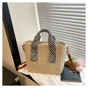 Détail d'un sac cabas en paille tissé avec poignée en foulard de soie et bandoulière en cuir