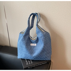 Detail of blue jacquard canvas tote bag with woven texture and metal buckle closure