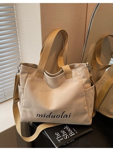 Minimalist beige canvas tote bag with side pockets and adjustable shoulder strap