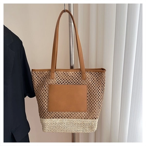 Detail of large straw tote bag featuring contrast stitching and a brown leather pocket