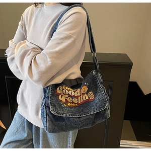 Detail of vintage denim messenger bag with colorful embroidery and wide shoulder strap