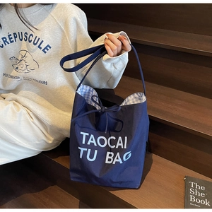 Détail du sac cabas en toile marine avec nœud de serrage et doublure à carreaux