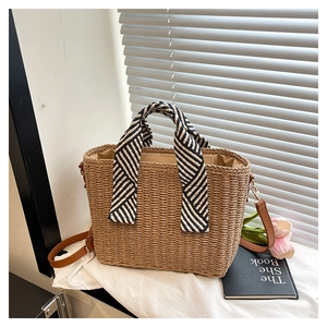 Détail du sac cabas en paille tissé avec poignées rayées noir et blanc et bandoulière cuir
