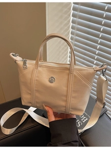 Chic beige canvas crossbody bag with silver logo shown from a 45-degree angle