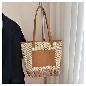 Detail of summer straw tote bag with bicolor weave design and brown leather straps