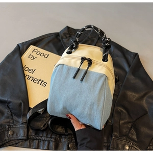 Close-up of mini two-tone denim bag showing braided handles and dual zipper details